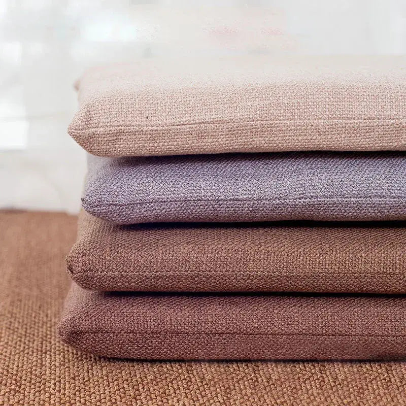 Stack of four beige and brown non-slip decorbites linen seat cushions made of textured woven fabric for dining chairs