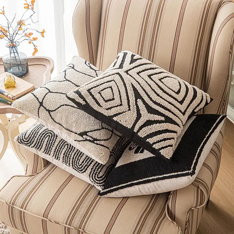 Three textured beige and brown cushion covers with decorbites geometric line art stacked on a striped armchair