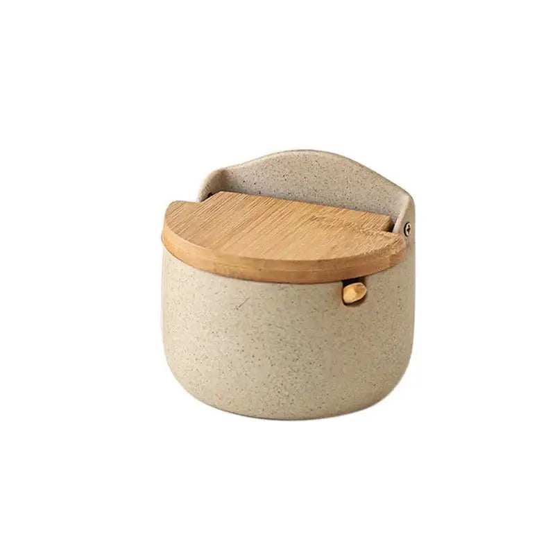 Beige ceramic seasoning jar from decorbites with speckled design, bamboo lid, and gold-tone metal clasp for kitchen use