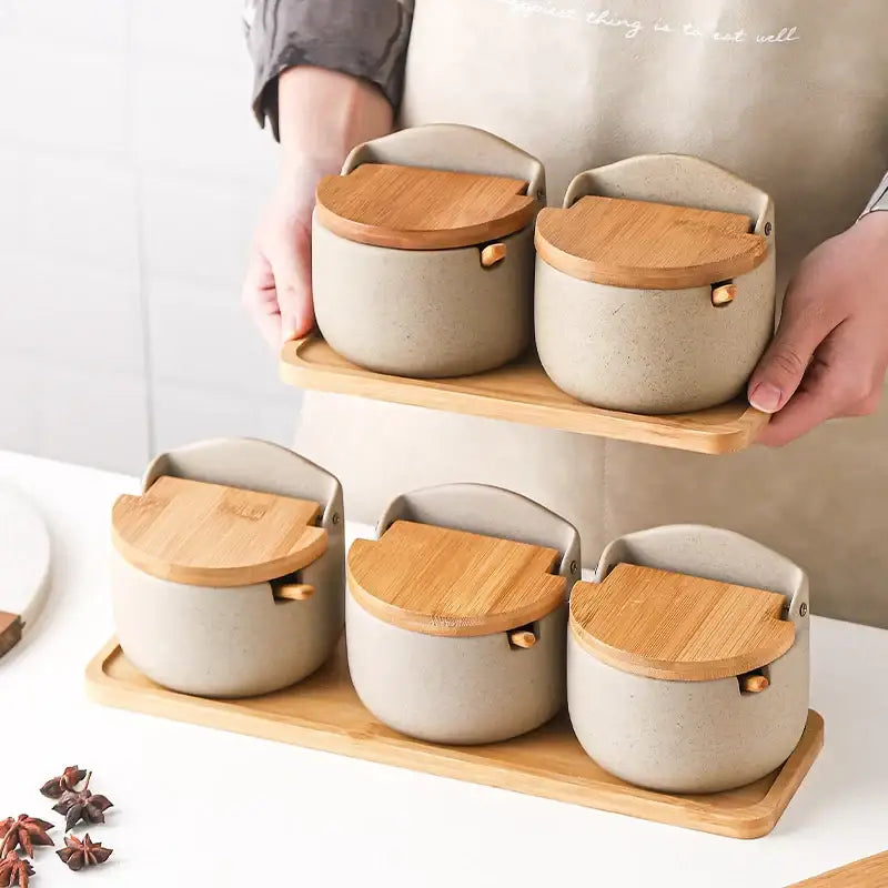 Beige ceramic seasoning jar set with bamboo lids and handles arranged on wooden trays for decorbites ceramic seasoning use