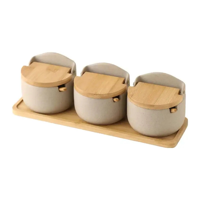Beige ceramic seasoning jar set with bamboo lids and wooden handles on a matching bamboo tray decorbites ceramic seasoning