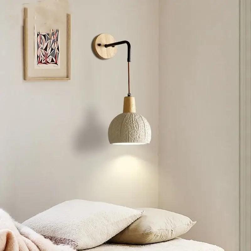 Beige ceramic wall sconce with pull chain switch featuring off-white shade, natural wood base, and black metal arm for bedroom