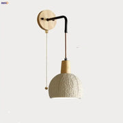 Beige ceramic wall sconce with textured pendant lamp, wooden mount, black arm, and pull chain switch for bedroom