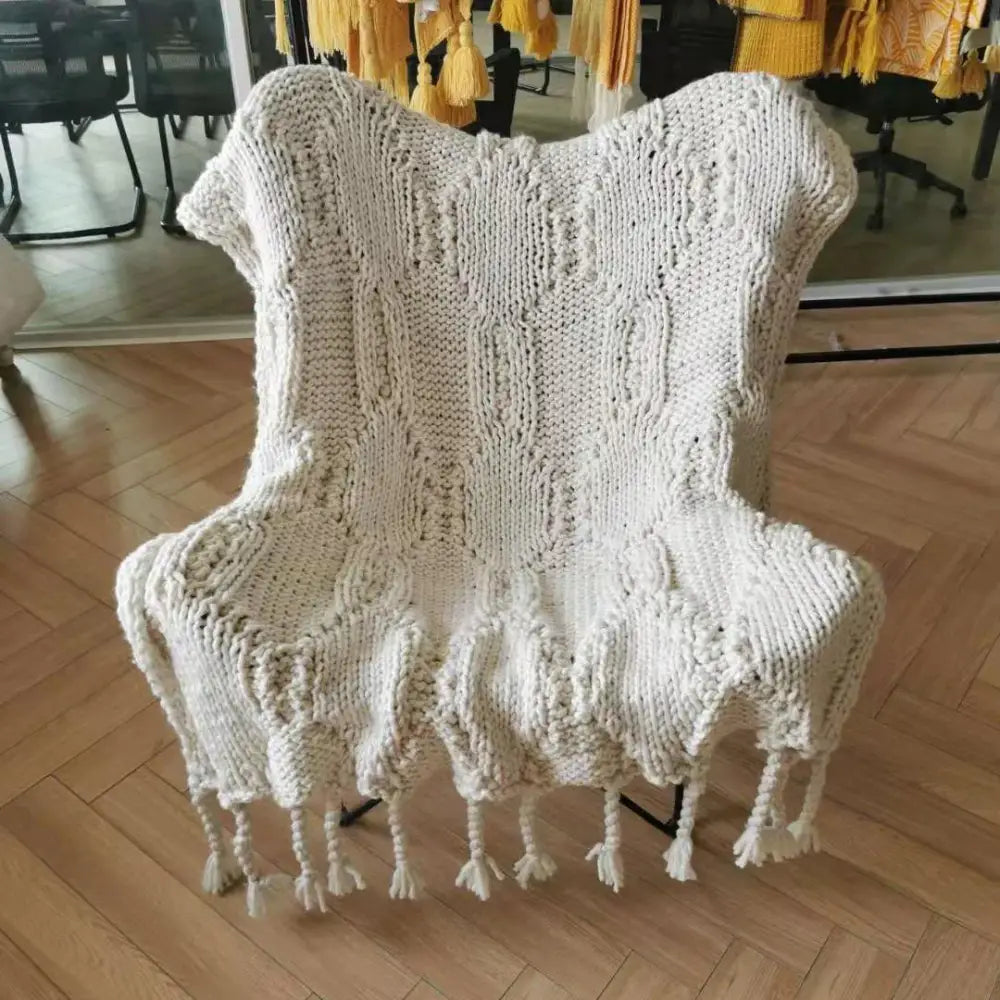 Beige chunky knit tassel throw blanket with textured cable pattern draped over armchair for cozy decorbites beige chunky decor