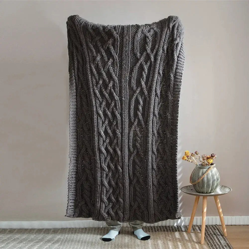 A thick dark gray knitted throw blanket with a prominent cable knit pattern for decorbites beige chunky knit tassel decor