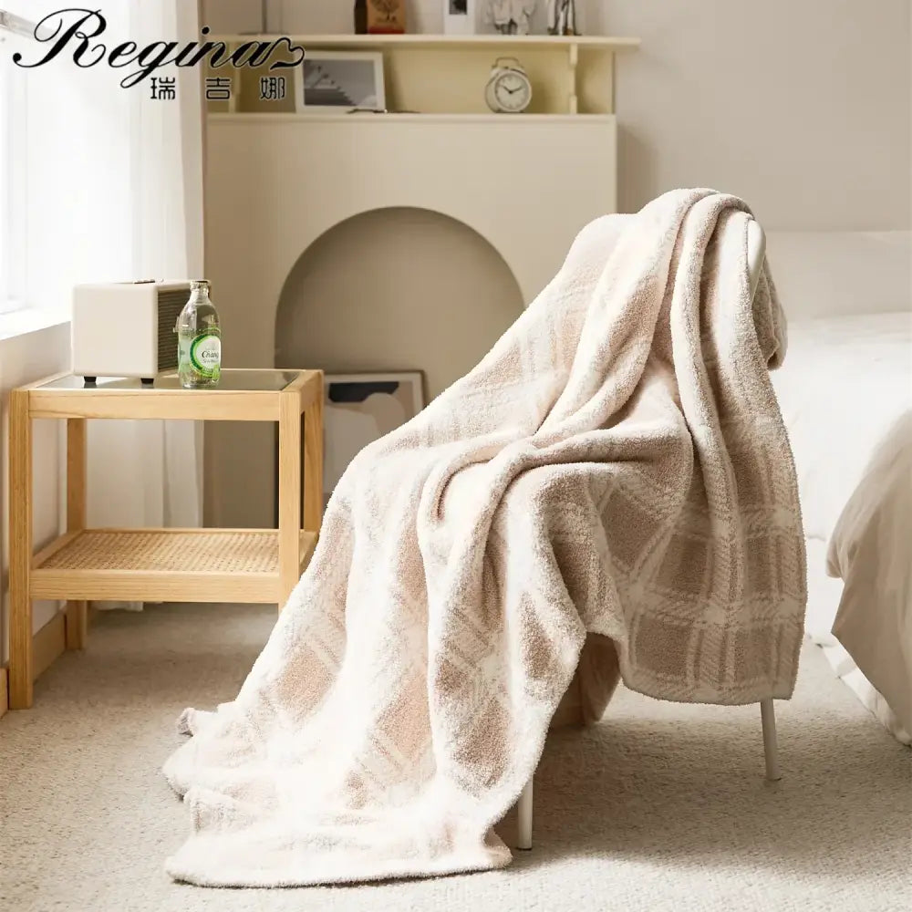 A soft cream-colored microfiber throw blanket with beige fluffy stripe plaid draped over the back of a chair