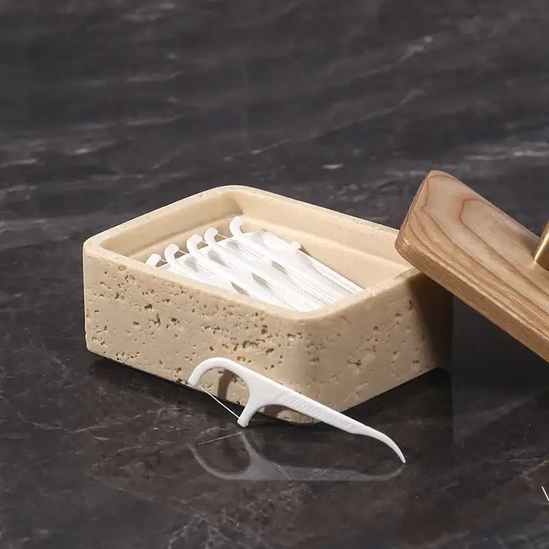 Beige textured natural stone container holding white dental floss picks in a double decker jewelry organizer bathroom storage