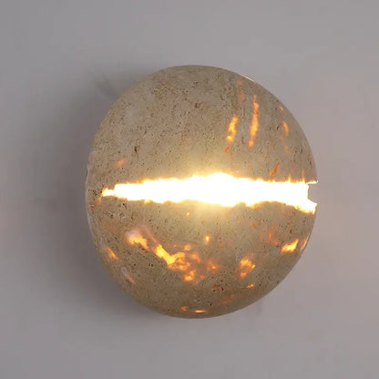 Beige dino egg stone wall lamp with gold accent featuring a round textured concrete sconce and warm horizontal slit light