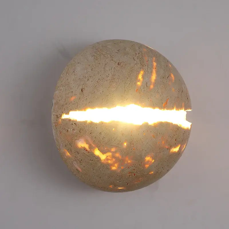 Beige dino egg stone wall lamp with gold accent featuring a round textured concrete sconce and warm horizontal slit light