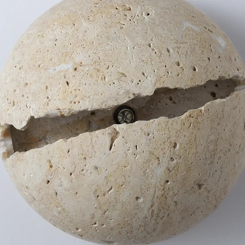 Beige dino egg stone wall lamp with gold accent featuring a split design revealing an embedded bulb by decorbites