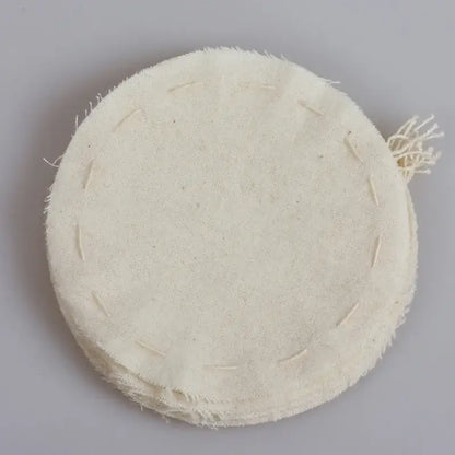 Beige eco-friendly flannel cloth coffee filter with off-white circular shape, frayed edges, and visible stitching in kitchen set