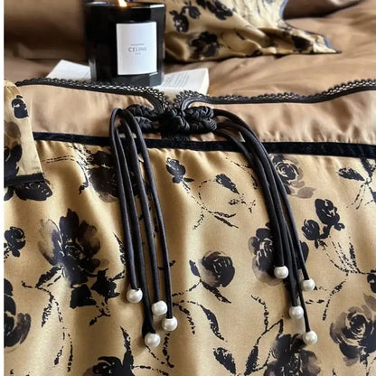 Black braided cord with pearl-tipped ends and decorative knot on beige floral decorbites cotton patchwork bedding set