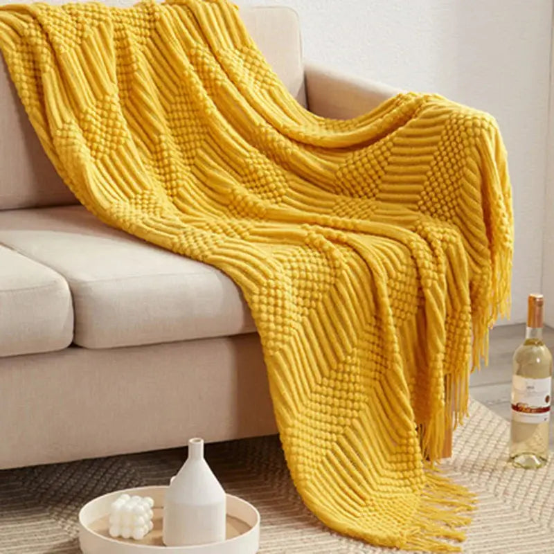 A cozy mustard-yellow decorbites 3d knitted tassel blanket with textured pattern and fringe for bedroom decor