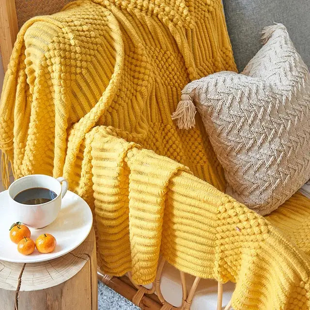 A cozy mustard-yellow decorbites 3d knitted tassel blanket with ribbed texture and tassel trim for bedroom decor