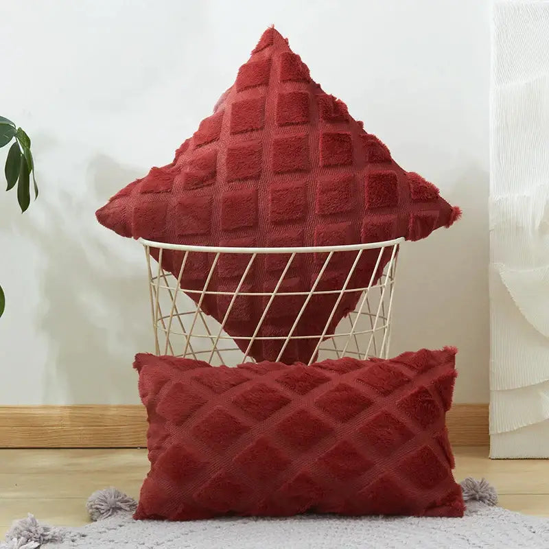 A plush deep red cushion with a geometric diamond pattern sits in a white wire basket for living room use
