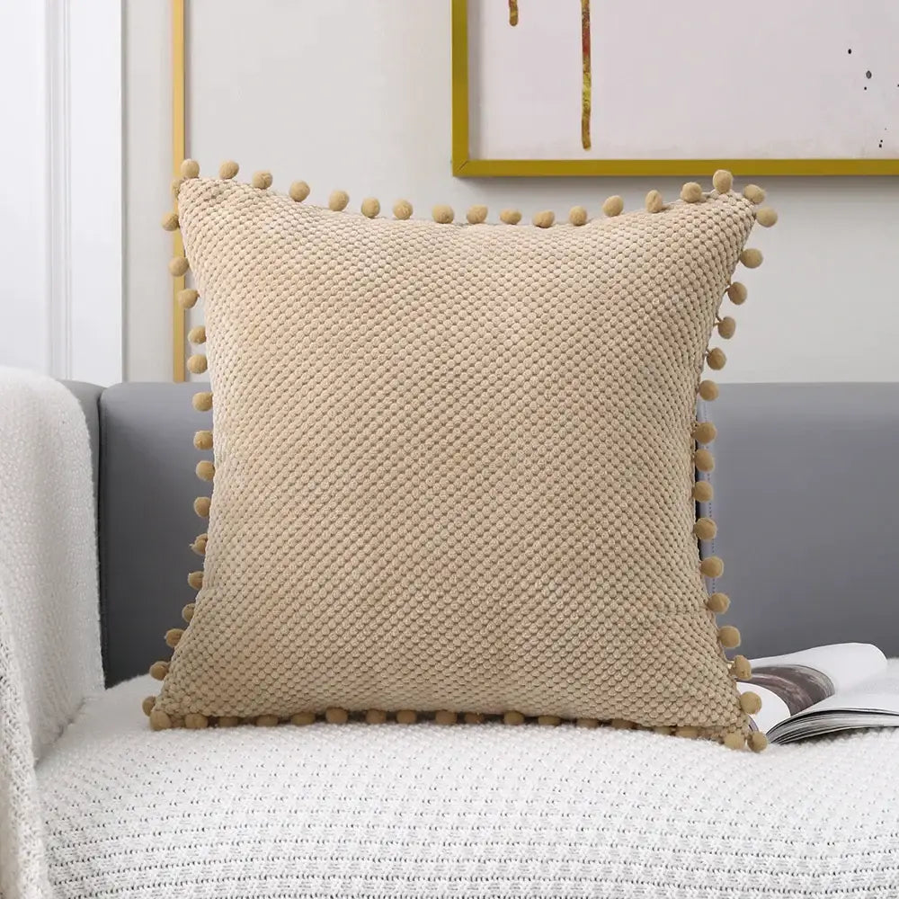 Beige knitted decorative pillow cover with textured fabric and soft pom-pom trim for living room decor
