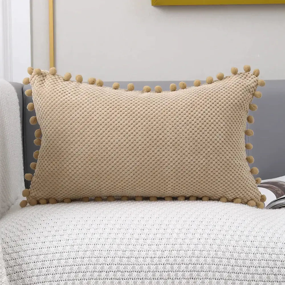 Beige knitted decorative pillow cover with textured diamond pattern and soft pom-pom trim for living room decor