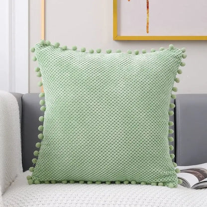 Light green knitted decorative pillow cover with textured woven pattern and pom-poms for living room decor