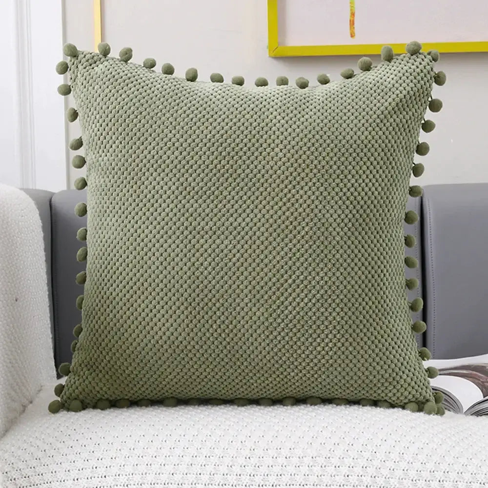 A soft sage green knitted decorative pillow cover with diamond texture and pom-poms for living room decor