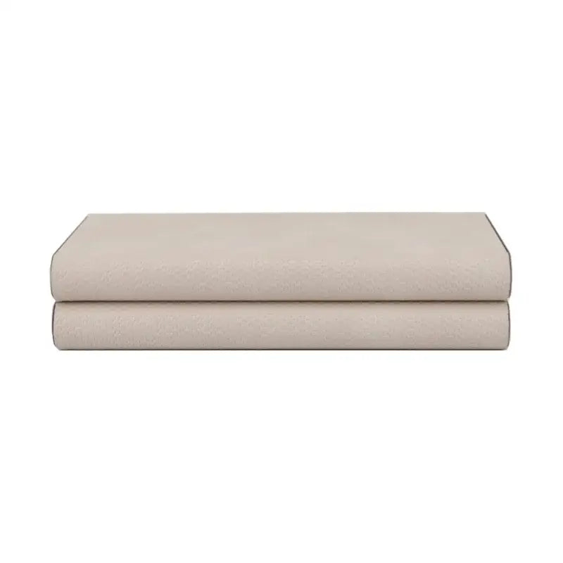 A beige leather jewelry box storage container with silver hinges is shown on neatly folded beige cotton bed sheets