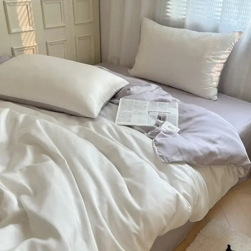A soft white satin pillow with a smooth surface on a beige and light blue ice silky solid bedding set by decorbites