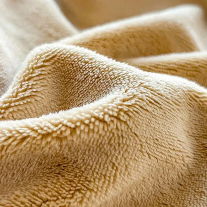 Cream-colored plush fleece blanket with soft textured surface complementing beige milk velvet fitted sheet and mattress topper