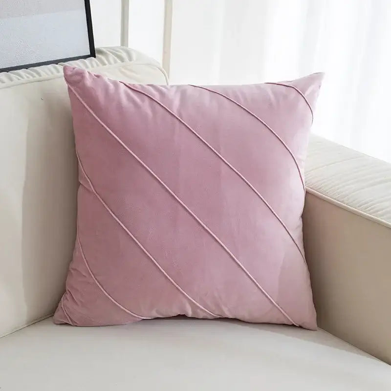 A soft pink velvet throw pillow with diagonal stitching featuring hand pleat embroidered design for living room use