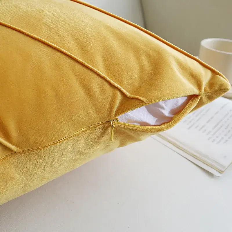 A plush mustard-yellow velvet pillow with hand pleat embroidered detail and zipper closure for living room use