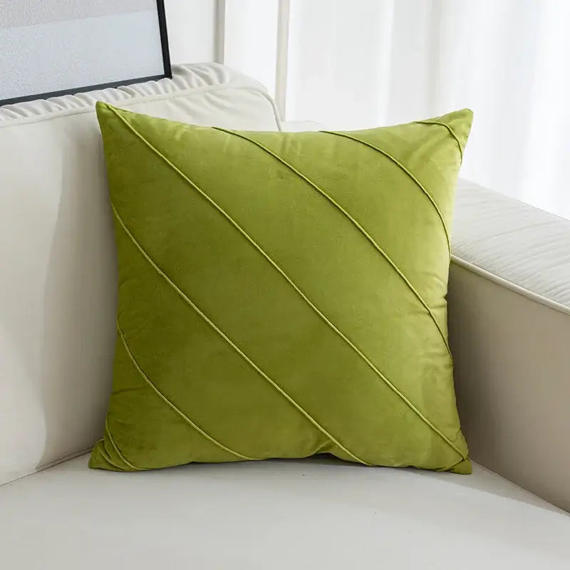 Olive green velvet square pillow with diagonal quilted lines featured among hand pleat embroidered cushions