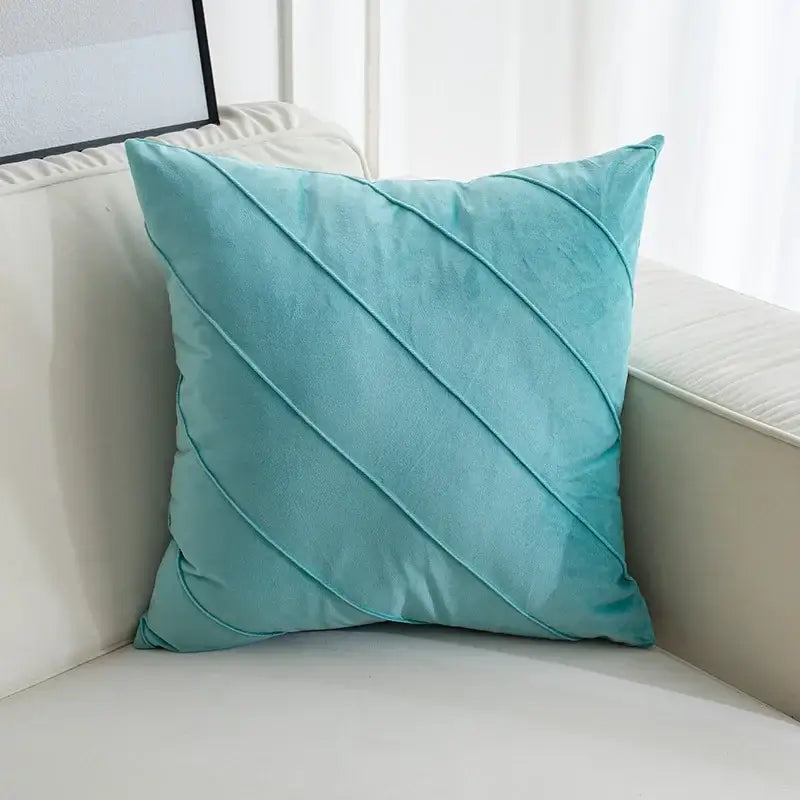 A soft teal velvet throw pillow with hand pleat embroidered diagonal stitched pleats for living room use