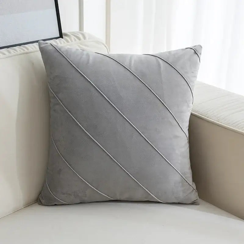 A soft gray velvet throw pillow with diagonal stitched lines featuring hand pleat embroidered detailing for living room use