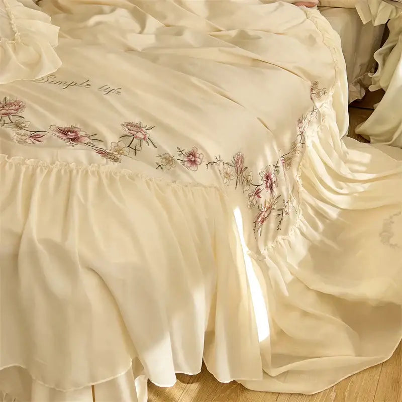 Cream-colored satin bed skirt with beige pink lace floral embroidery and ruffled hemline in decorbites bedding set