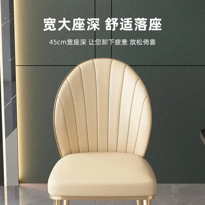 Cream-colored upholstered dining chair with curved vertically ribbed backrest and gold legs from decorbites dining set