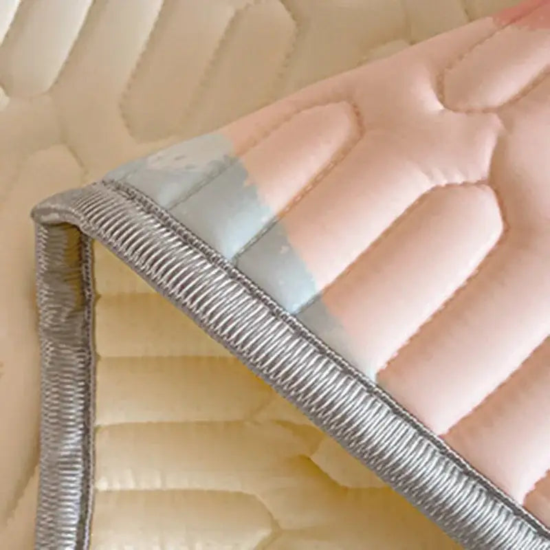 Pink and light blue quilted mattress pad with silver ribbed trim on beige and red decorbites cartoon pattern latex mattress