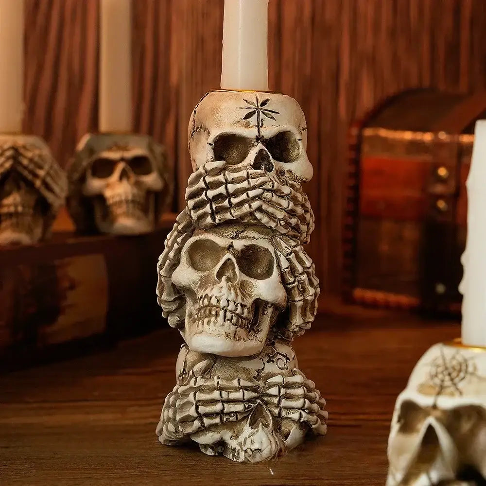 Beige resin bone skeleton candlestick holder featuring three stacked skulls with skeletal hands and intricate tattoos decorbites bone skeleton