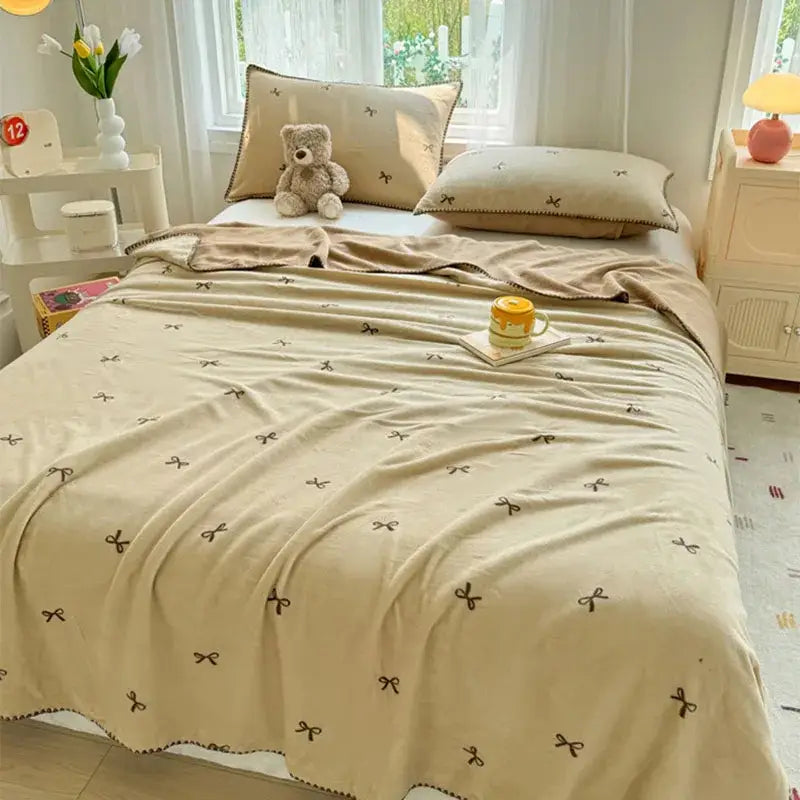 Beige scalloped cozy coral fleece blanket with small brown bow embroidery perfect for bedroom decorbites cozy coral use