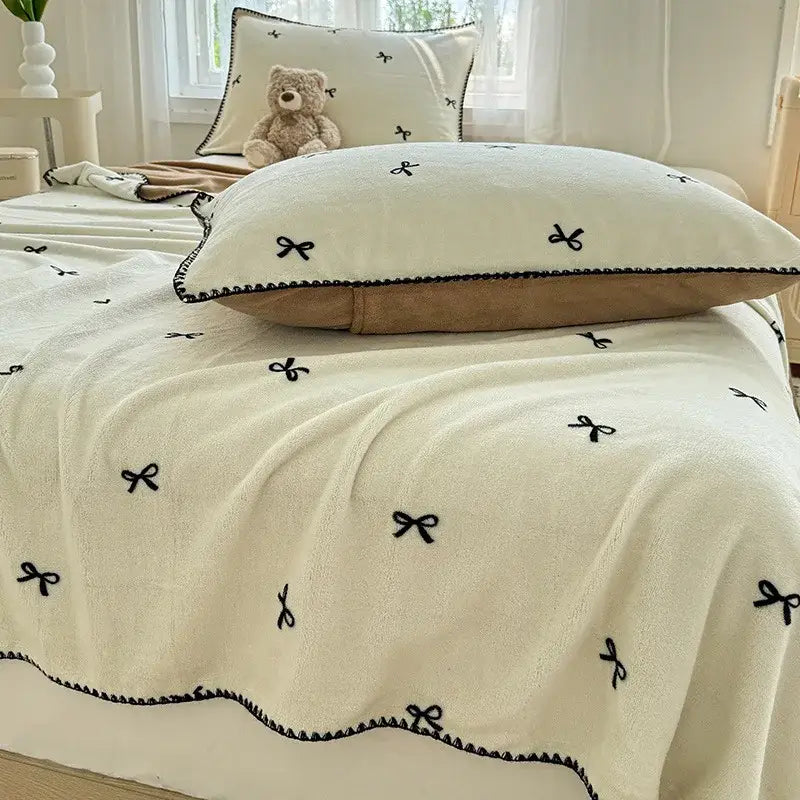 Beige scalloped cozy coral fleece blanket with black embroidered bow decor for bedroom use by decorbites cozy coral