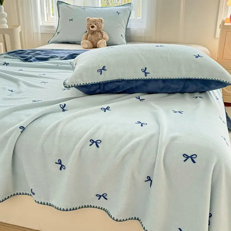 Beige scalloped cozy coral fleece blanket with light blue plush fabric navy blue embroidered bow decorbites cozy coral fleece