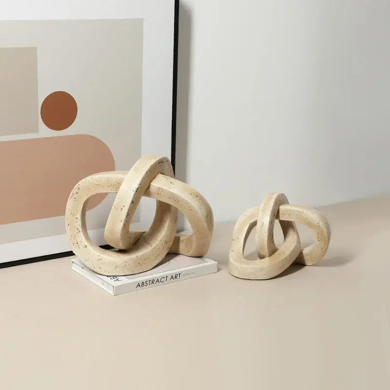 Beige speckled ceramic geometric interlocking loop knot sculpture with textured cream-colored finish for living room decor