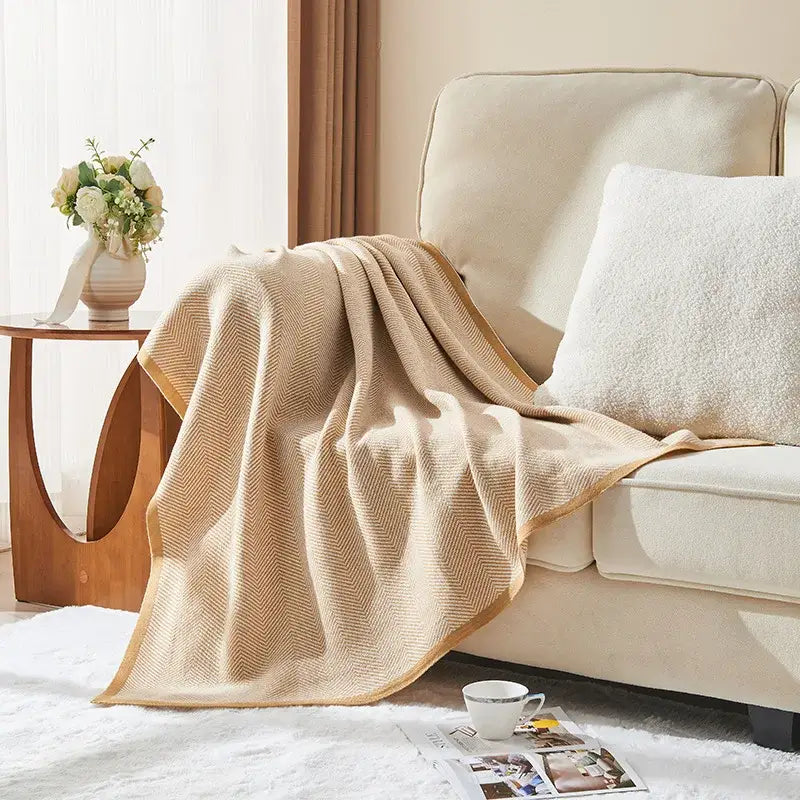 Beige and tan decorbites herringbone knit blanket with soft textured weave draped over cream-colored sofa