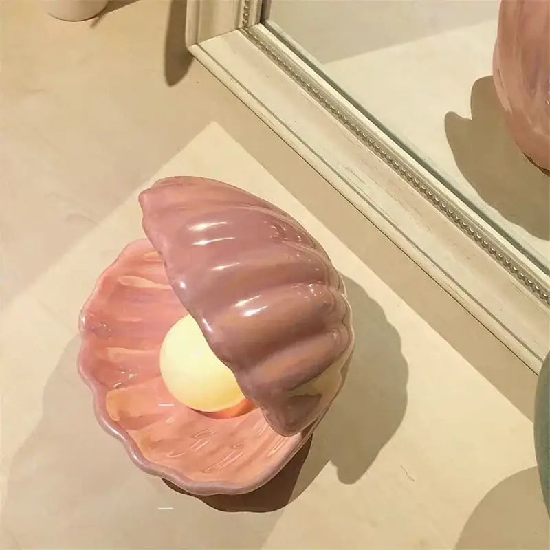 Glossy pink decorbites ceramic shell pearl night light featuring a warm yellow bulb in a clamshell design