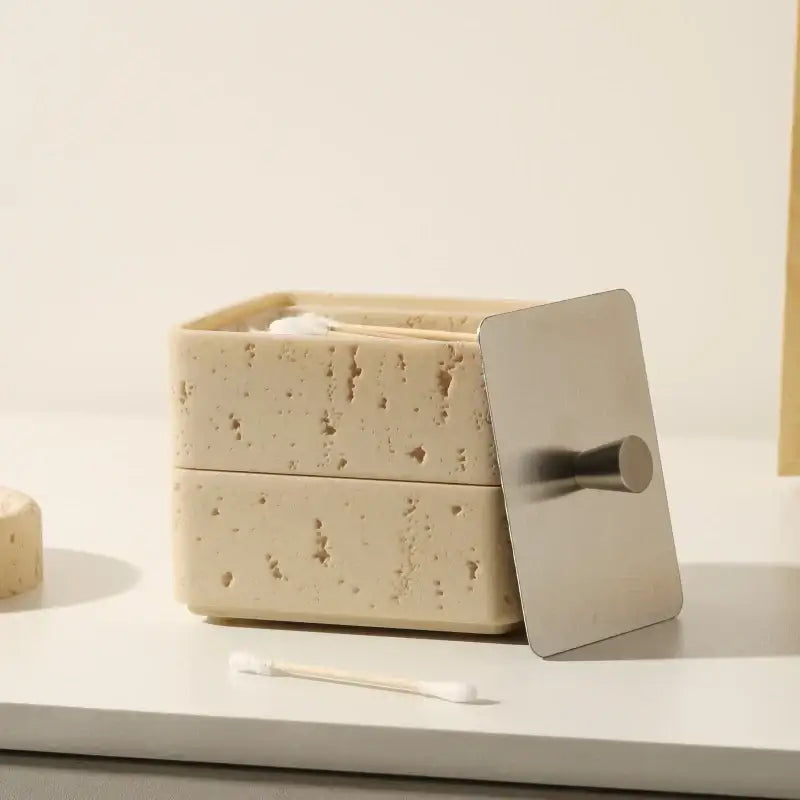 Beige textured natural stone double decker jewelry organizer with a sleek silver metal lid and handle for bathroom use