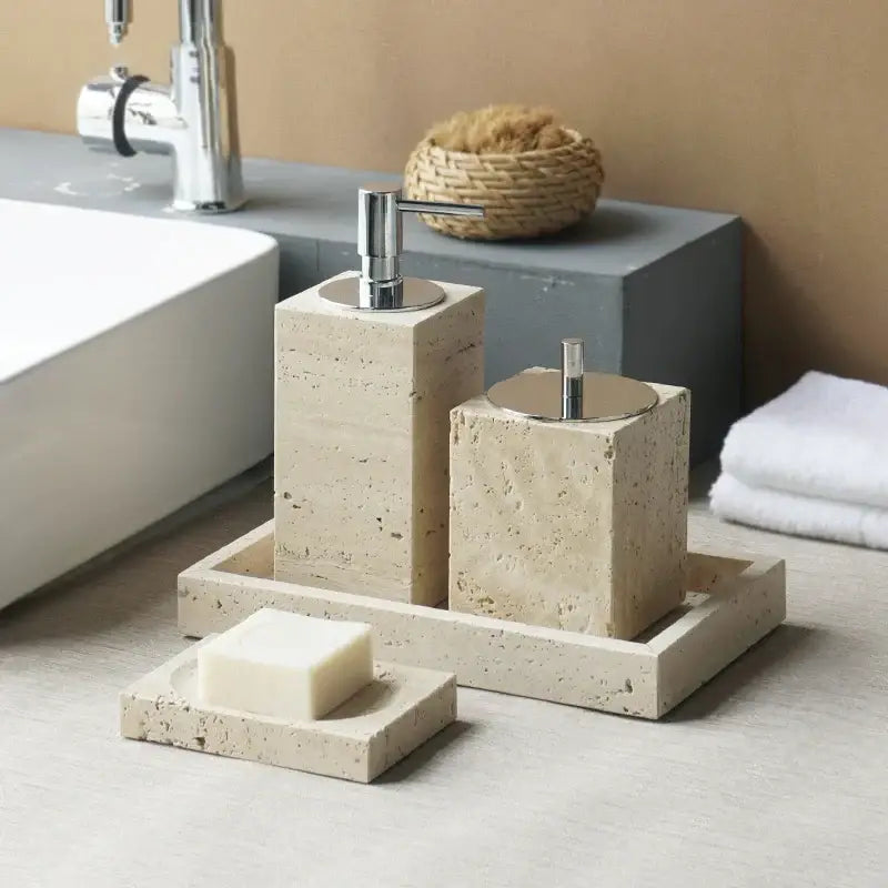 Beige travertine marble bathroom accessories set with sleek chrome pump and lid accents on a matching tray