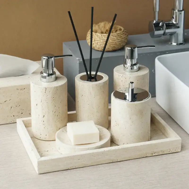 Beige travertine marble bathroom accessories set with tray including chrome-finished pump dispensers and soap dish