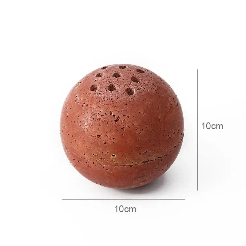 Beige travertine marble sphere incense burner with porous terracotta texture and small perforations for living room decor