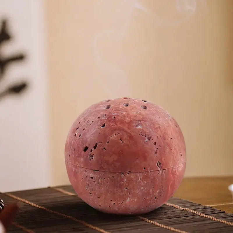 Beige travertine marble sphere incense burner with pinkish red lava stone texture and perforations for decorbites decor