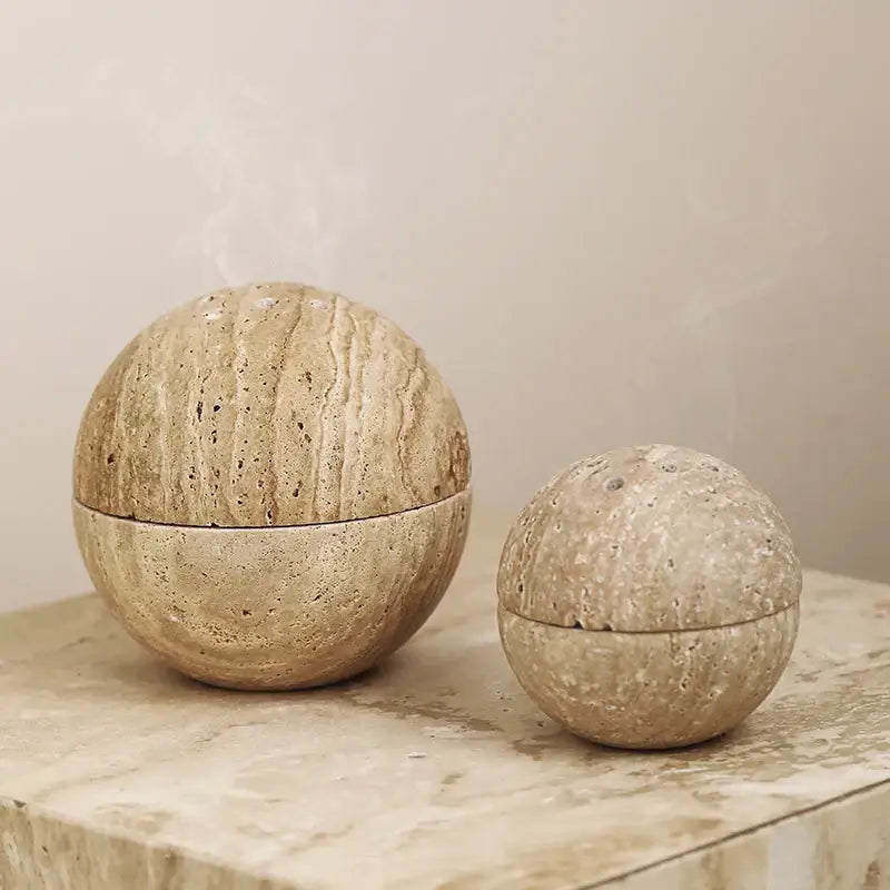 Two beige travertine marble incense burners in spherical shape with natural veining for living room decor by decorbites