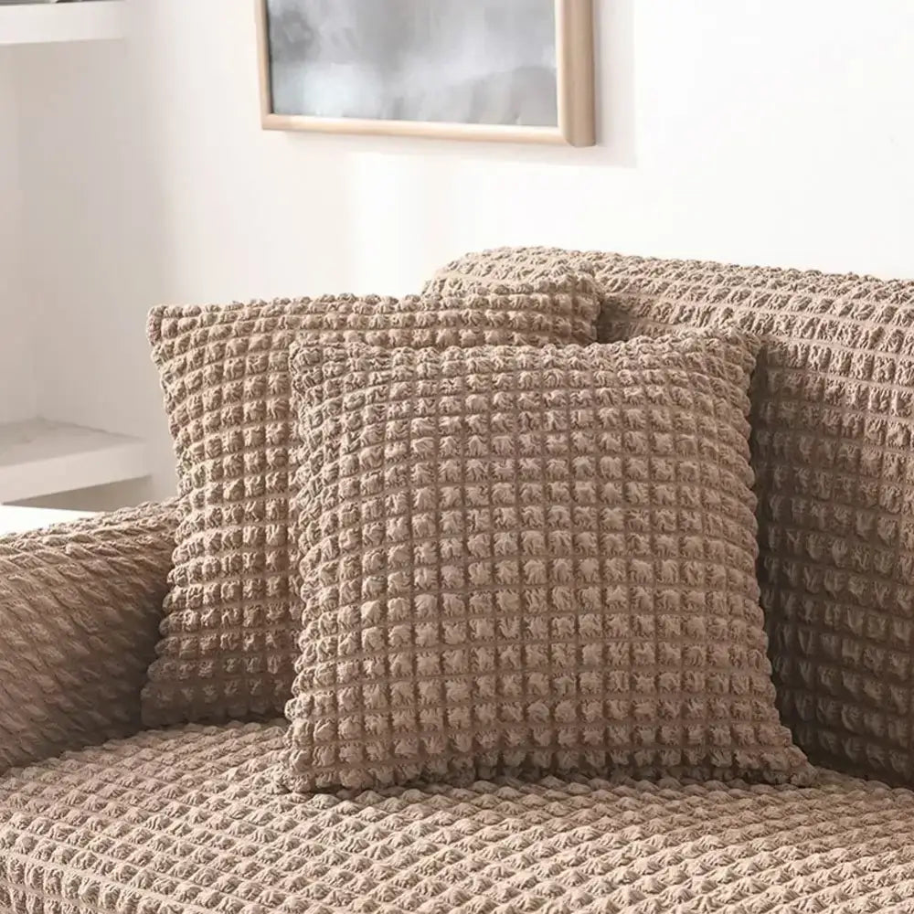 Beige textured cozy sofa cover with raised grid pattern and ruffled solid color design for living room use