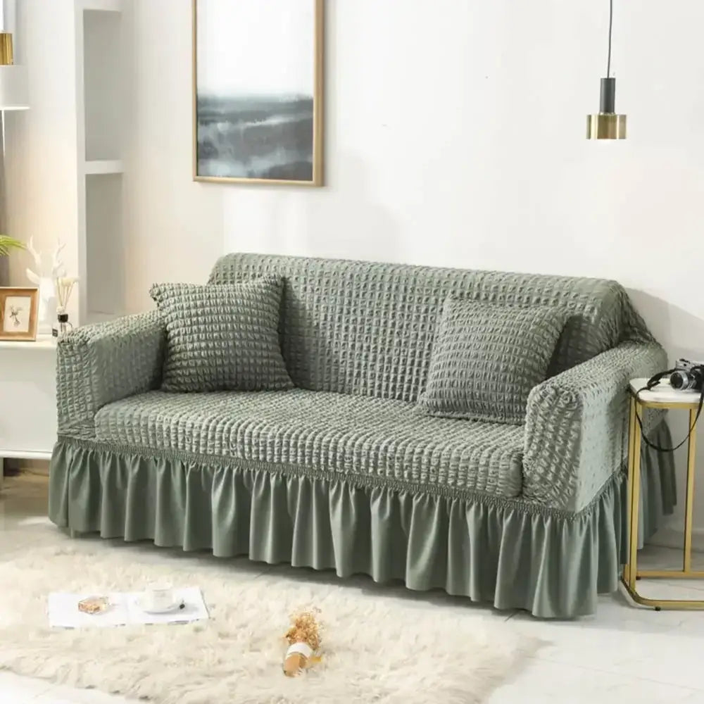 A sage green waffle-textured cozy sofa cover with ruffled hem ideal as a cozy sofa slipcover