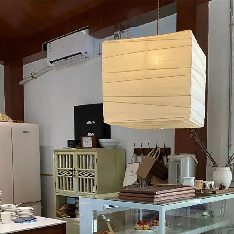Beige and white cube rice paper pendant lamp by decorbites hanging from a cord for living room decor